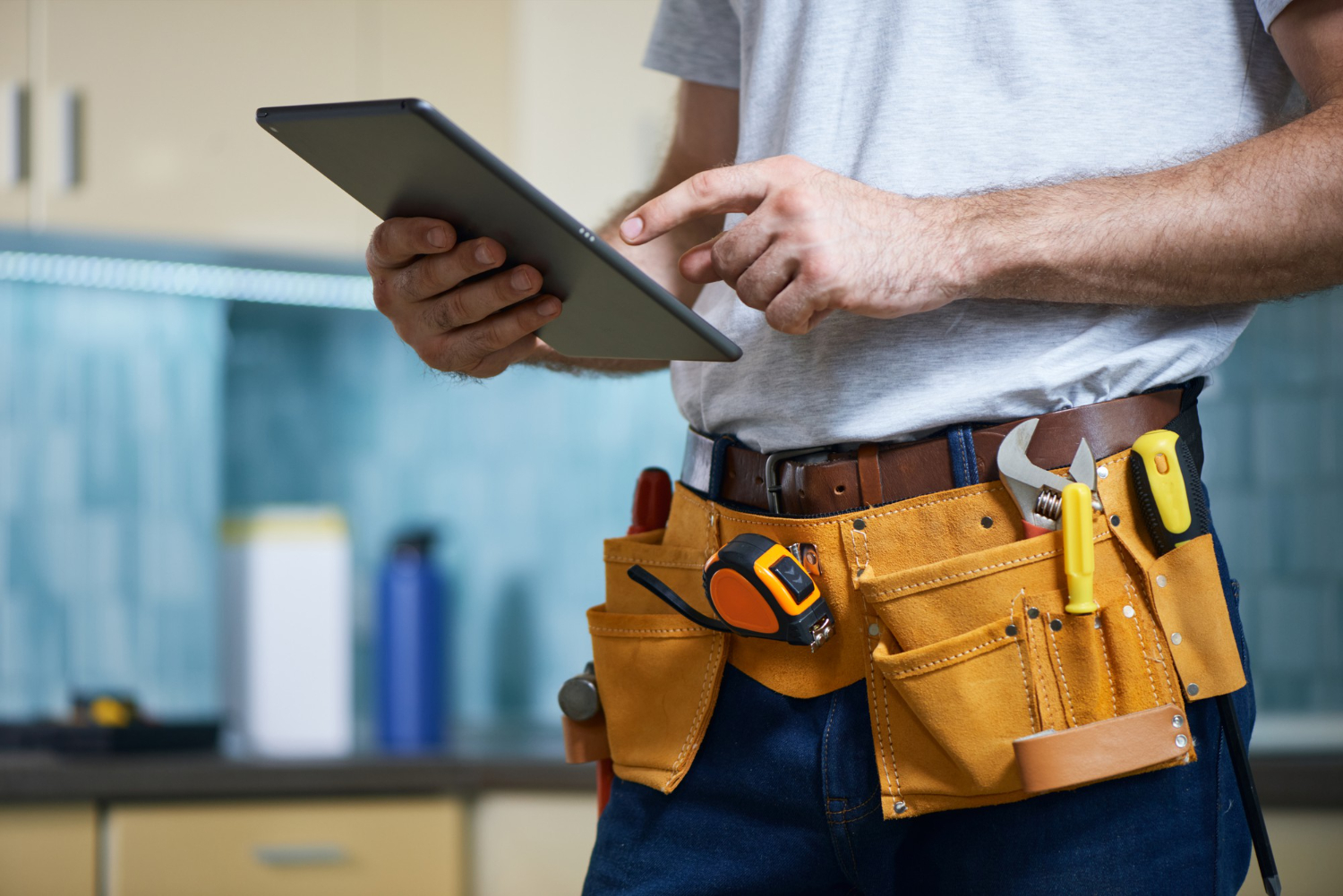A tradesperson using adminpal on a tablet, tool belt on